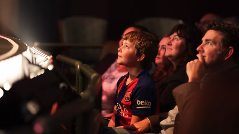 A young boy looking towards the stage from a seat