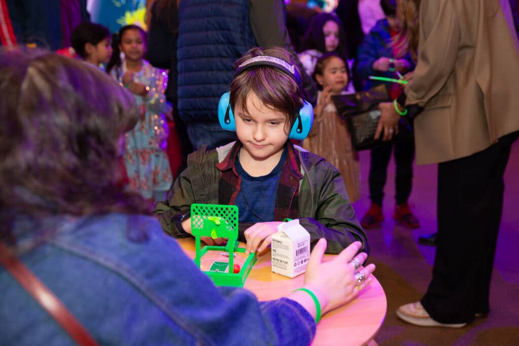 kid wearing ear defenders and doing an activity.