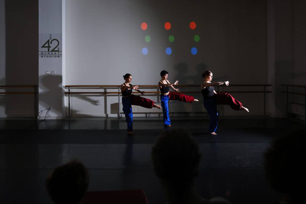 Three women performers wearing red and blue pants rehearsing in a New42 studio.