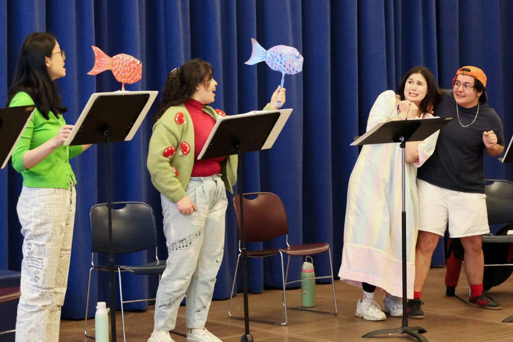 4 performers standing up with two hold a fish craft.