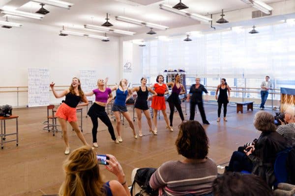 8 dancers in a line rehearsing in a studio 